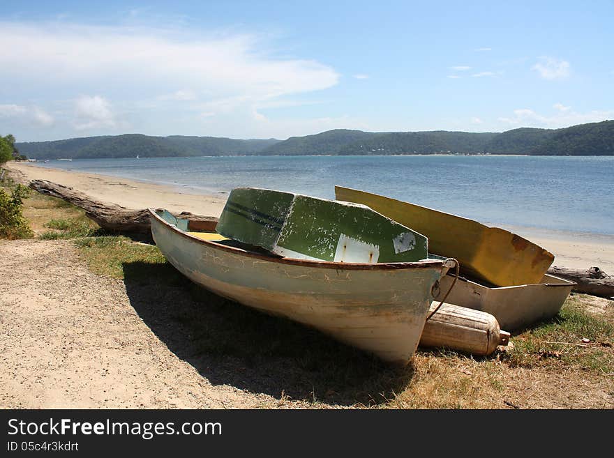 Old simple wooden boats on a tropical beach in australia near sydney with a tranquil ocean and blue sky. Old simple wooden boats on a tropical beach in australia near sydney with a tranquil ocean and blue sky