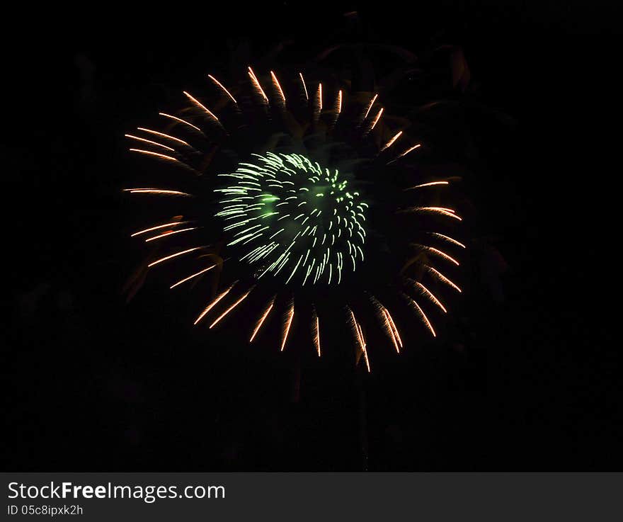 Fireworks formed in a circle of green lights surrounded by a circle of red lights against a black sky. Fireworks formed in a circle of green lights surrounded by a circle of red lights against a black sky