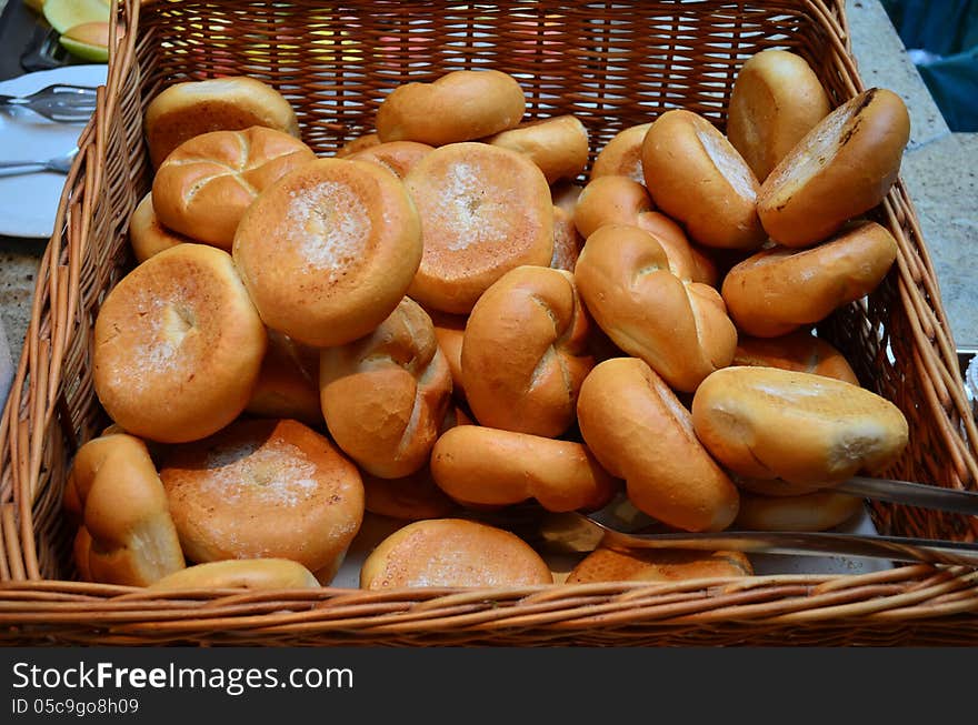 Lot of freshly baked buns in a wicker basket on a stone table. Lot of freshly baked buns in a wicker basket on a stone table