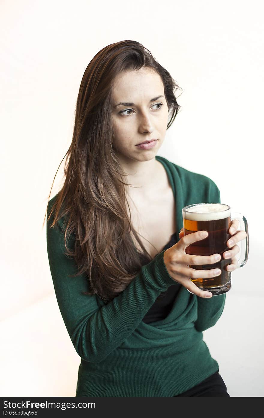 Beautiful young woman with brown hair and eyes holding a mug of beer. Beautiful young woman with brown hair and eyes holding a mug of beer.