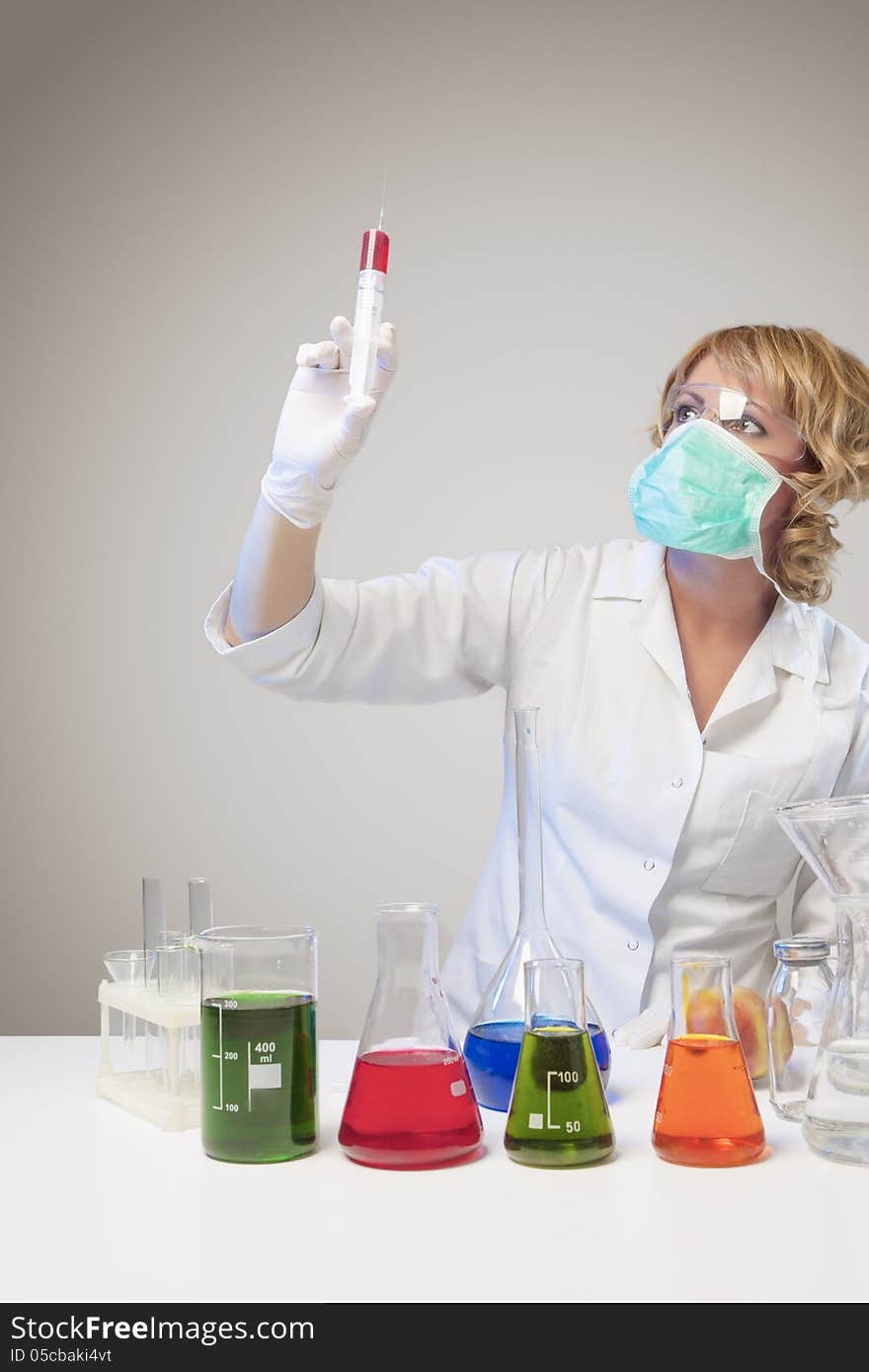 Portrait of female laboratory staff dealing with test syringe. isolated over gray background. vertical shot. Portrait of female laboratory staff dealing with test syringe. isolated over gray background. vertical shot