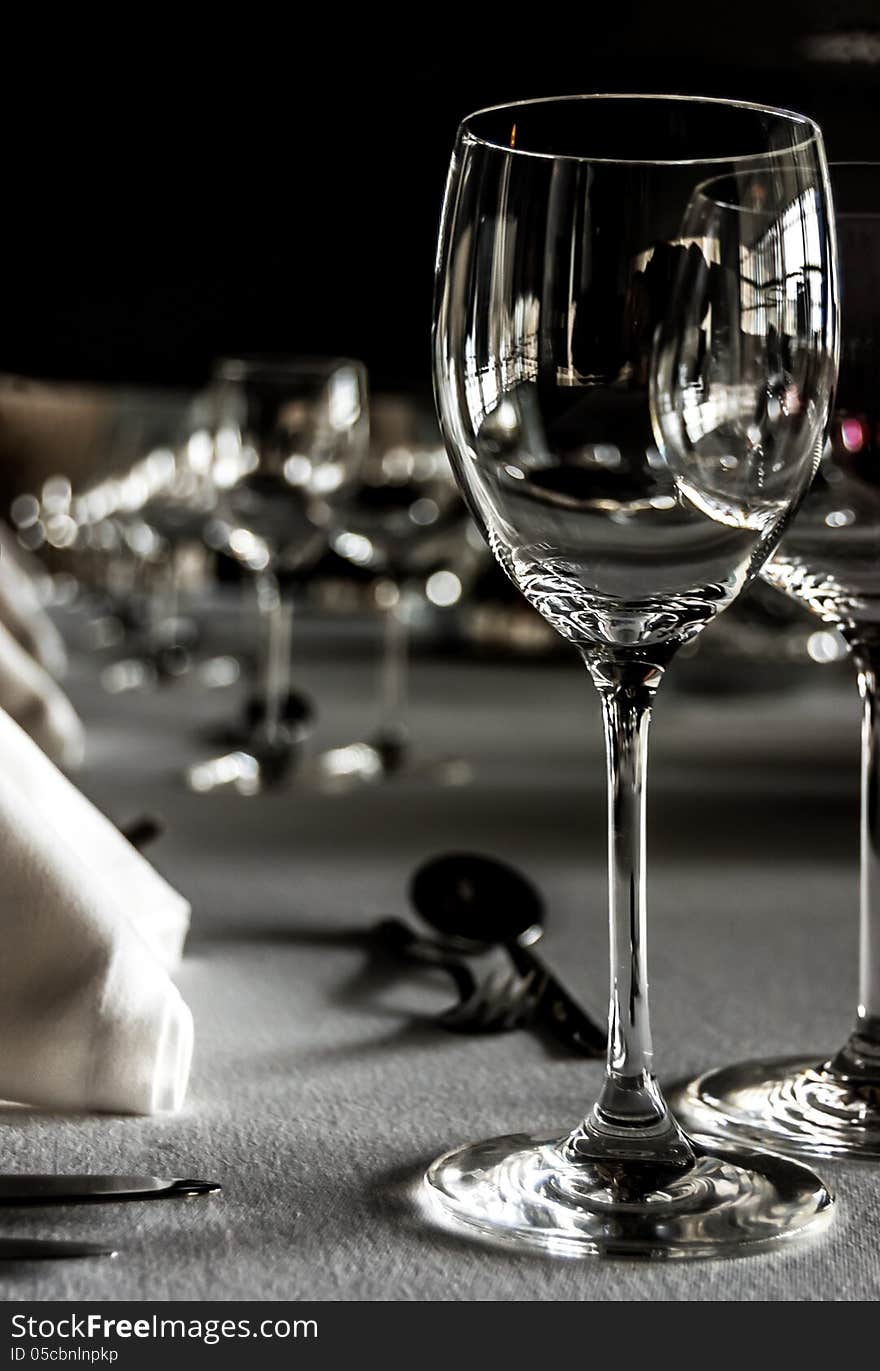 Black and white shot of a table setting with wineglasses, white napkins and silwerware on white tablecloth. Black and white shot of a table setting with wineglasses, white napkins and silwerware on white tablecloth.