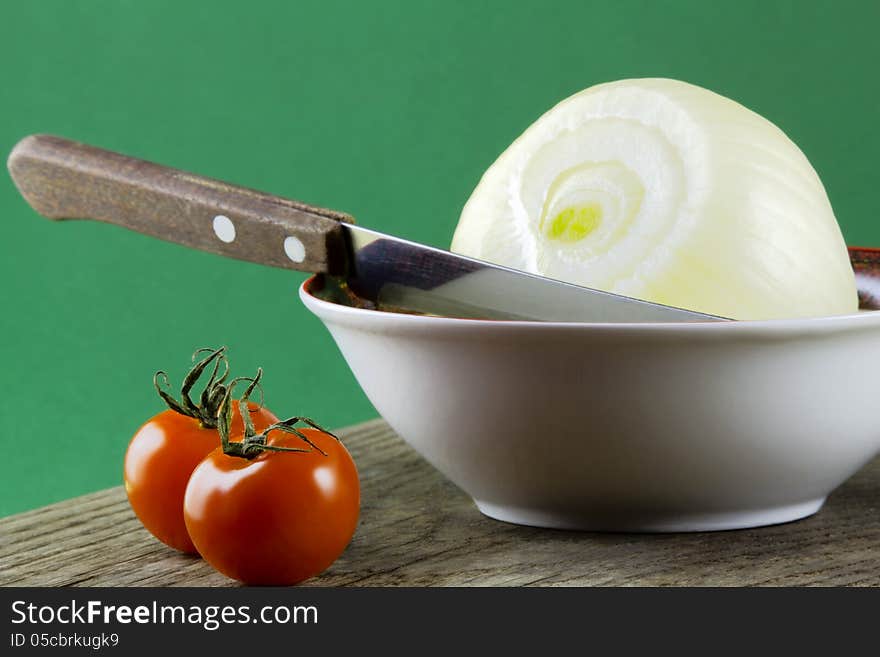 Tomatoes on the table and onion in a bowl, green background. Tomatoes on the table and onion in a bowl, green background