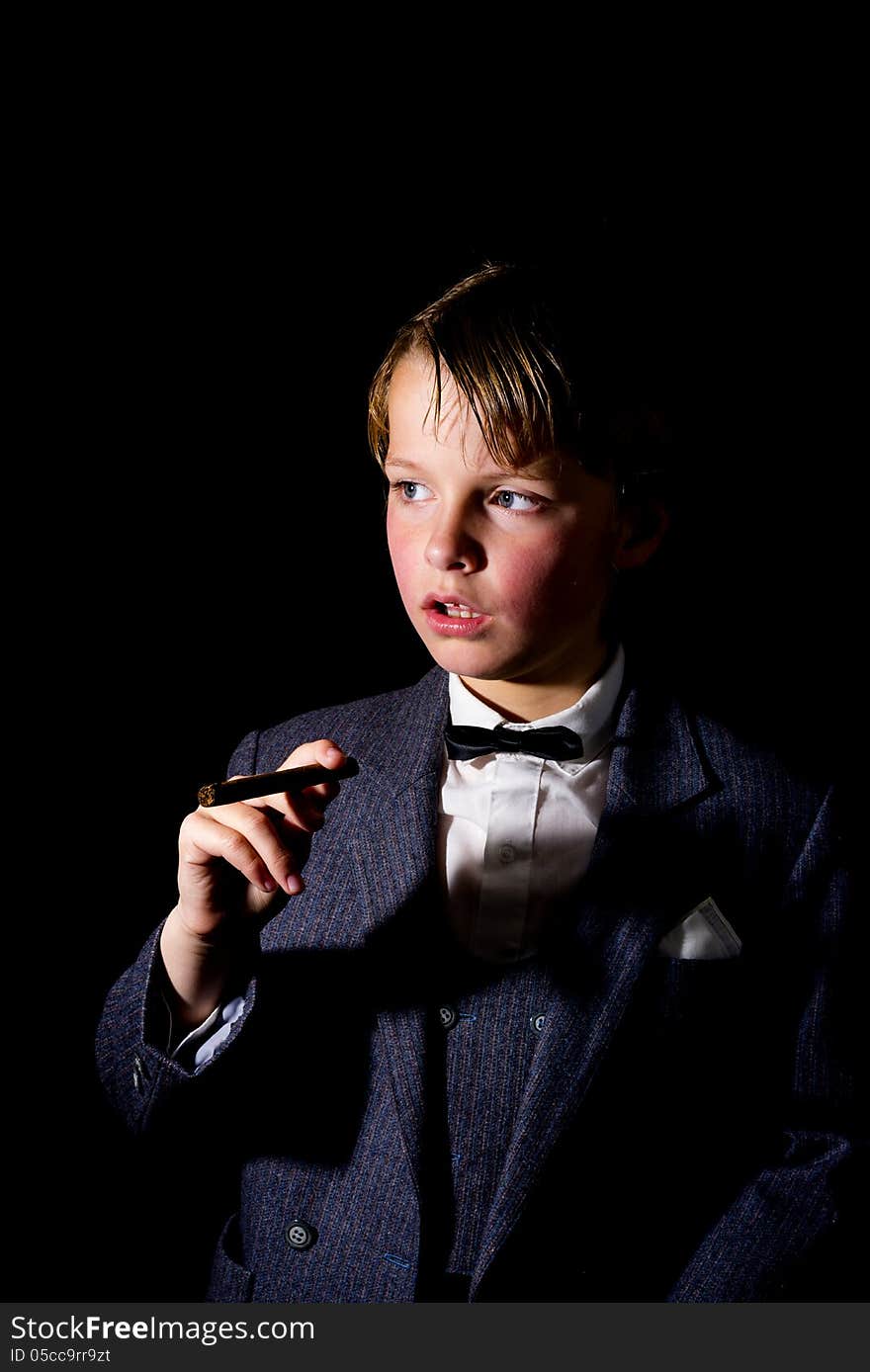 Boy in suit, holding a cigar. low key image. Boy in suit, holding a cigar. low key image.