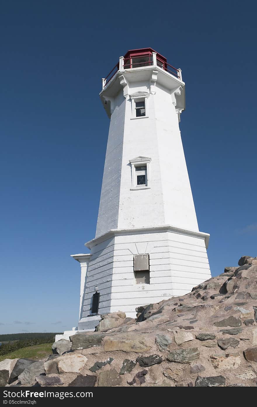 Louisbourg lighthouse with stone support in the foreground - intense blue sky good for copy space