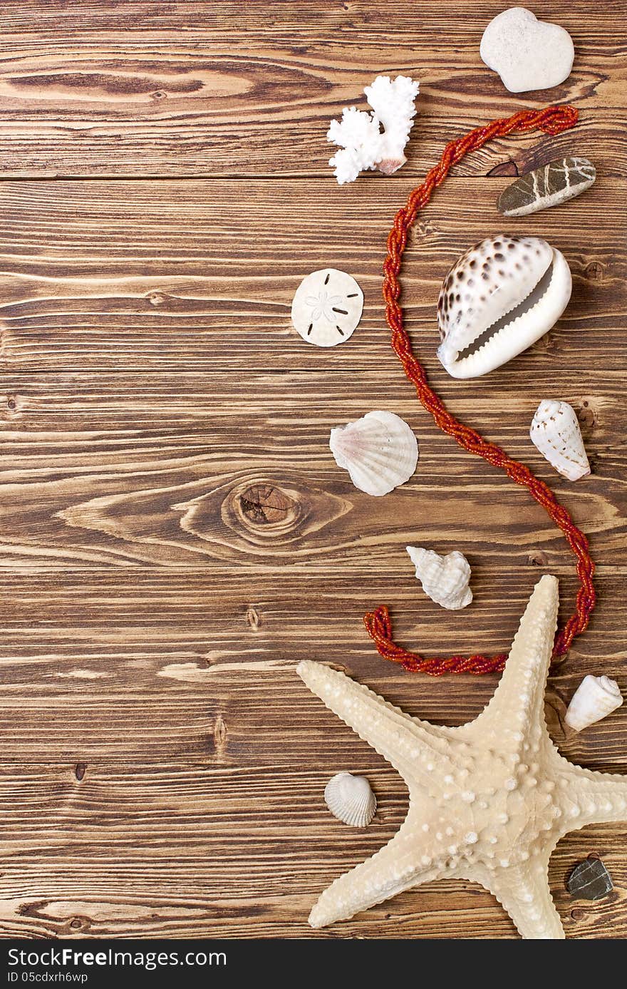 Starfish, shells, stones and coral beads on a brown wooden background. Starfish, shells, stones and coral beads on a brown wooden background