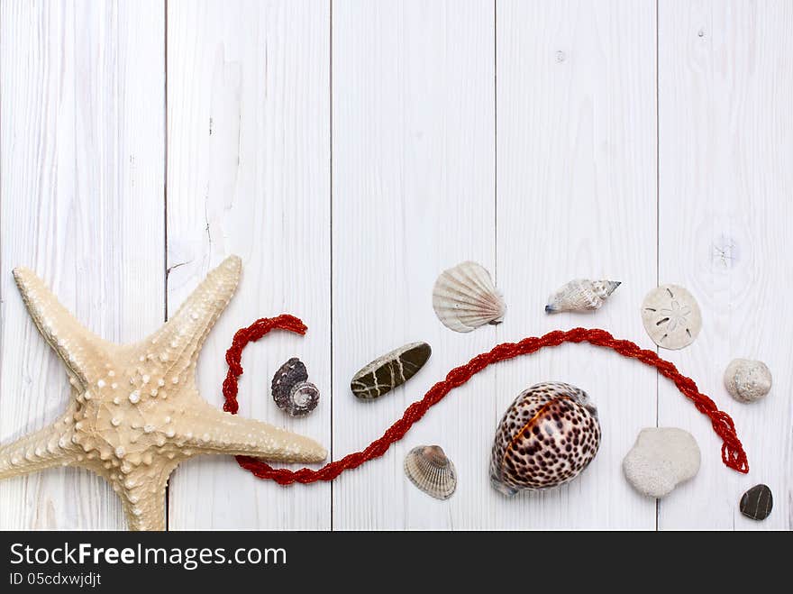 Starfish, shells, stones and coral beads on a white wooden background. Starfish, shells, stones and coral beads on a white wooden background