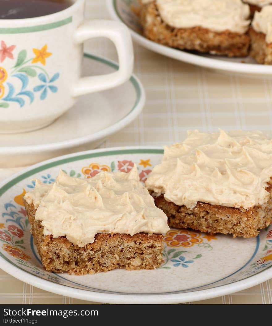 Two peanut butter bars on a plate with a cup of coffee