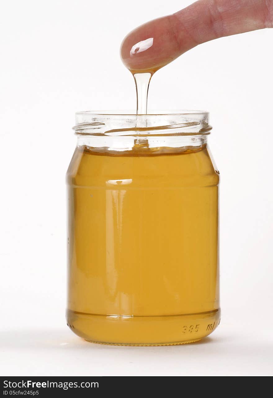 Honey pot and a finger on white background. Honey pot and a finger on white background