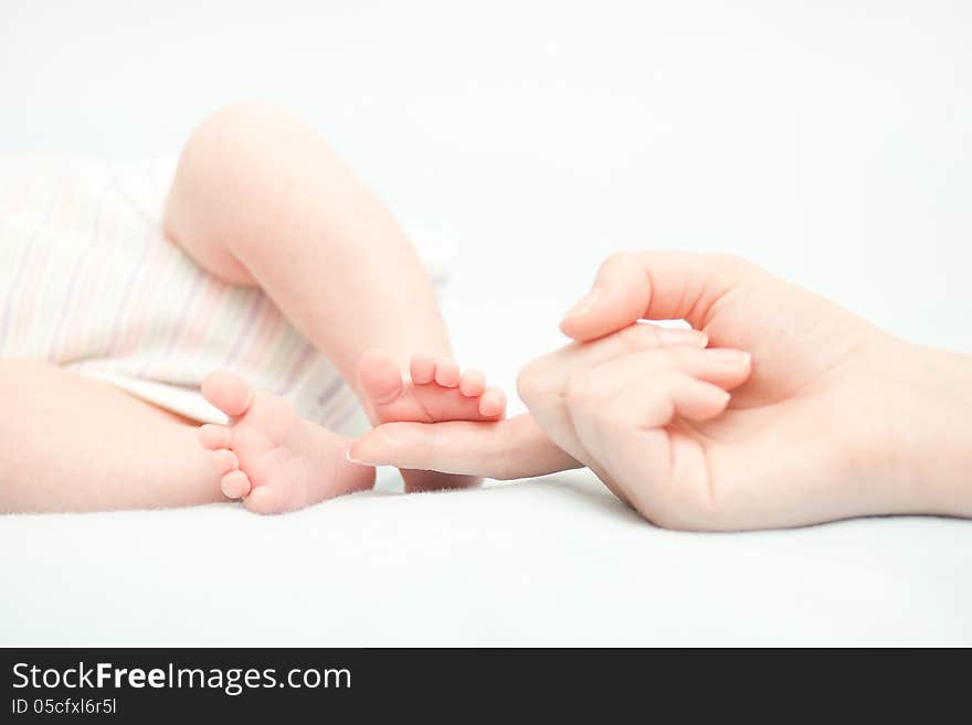 Little baby feet and hand of the mother