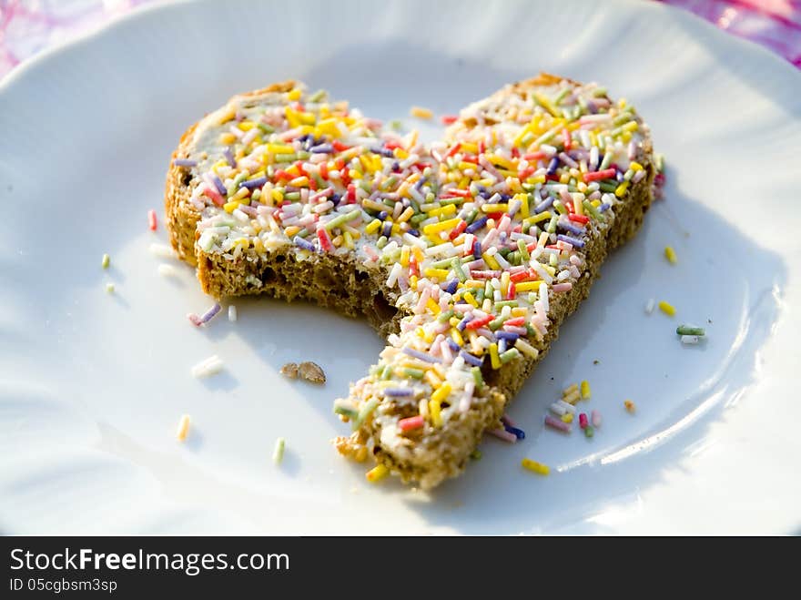 A heart-shaped slice of bread with sprinkles on it.