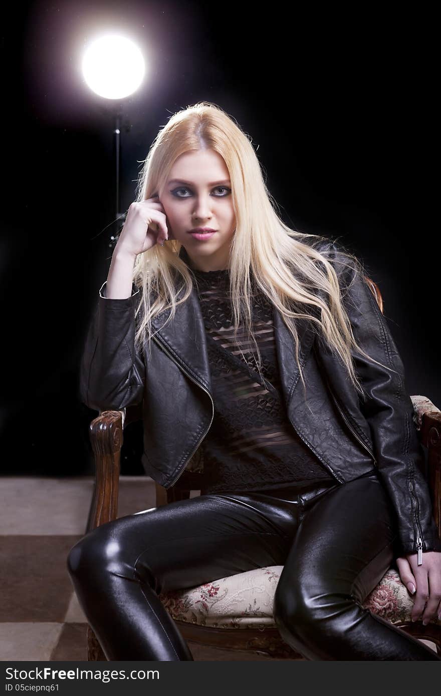 Blonde in a vintage chair with a light behind studio shot