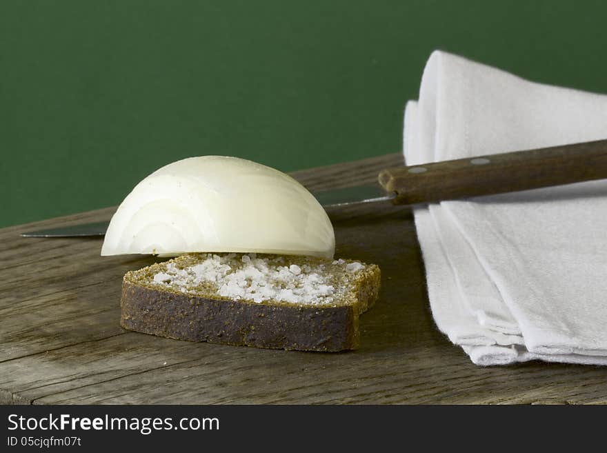 On the old wooden table rye bread with salt and the onions, green background