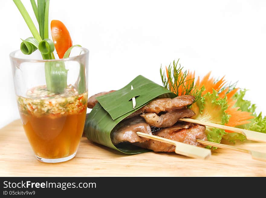 Roast pork wrapped in banana leaves and served with seafood sauce