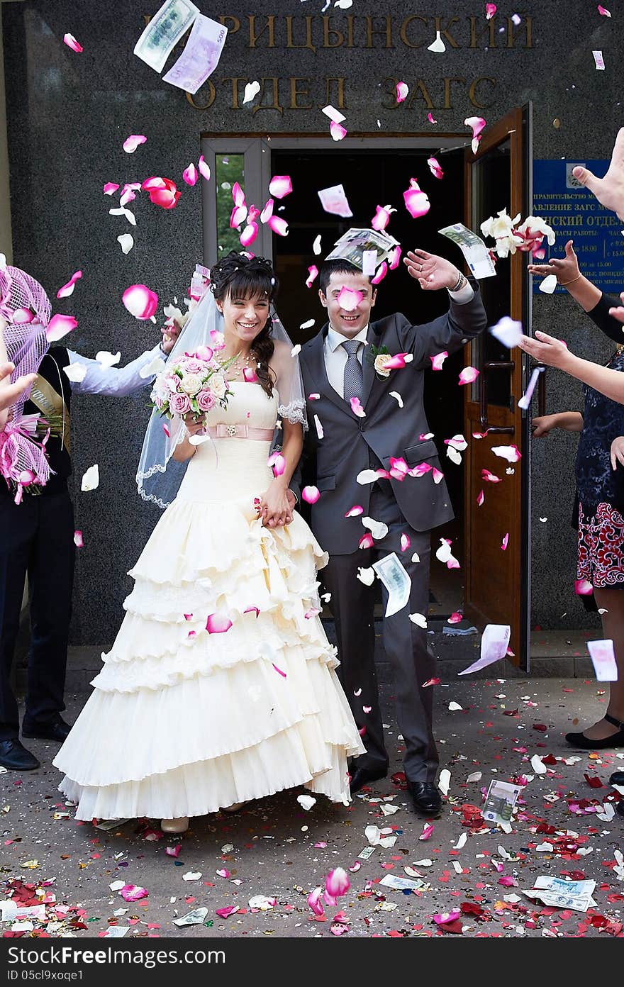 Happy newlyweds and flying petals after the registry office