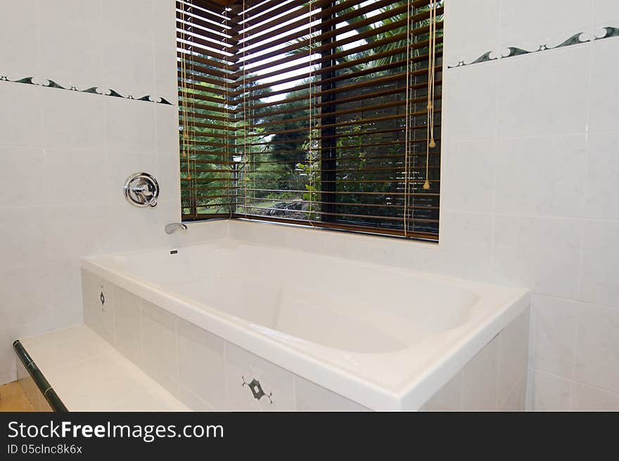 Modern bathroom with white tiles and a window.