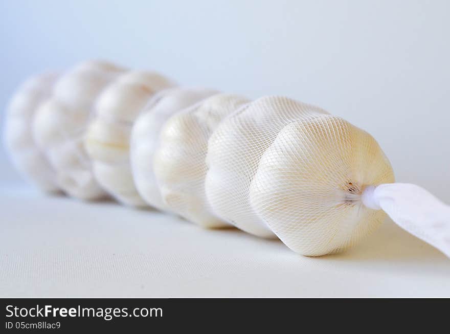 Seven fresh garlics in a bag on white background with copy space. Seven fresh garlics in a bag on white background with copy space.