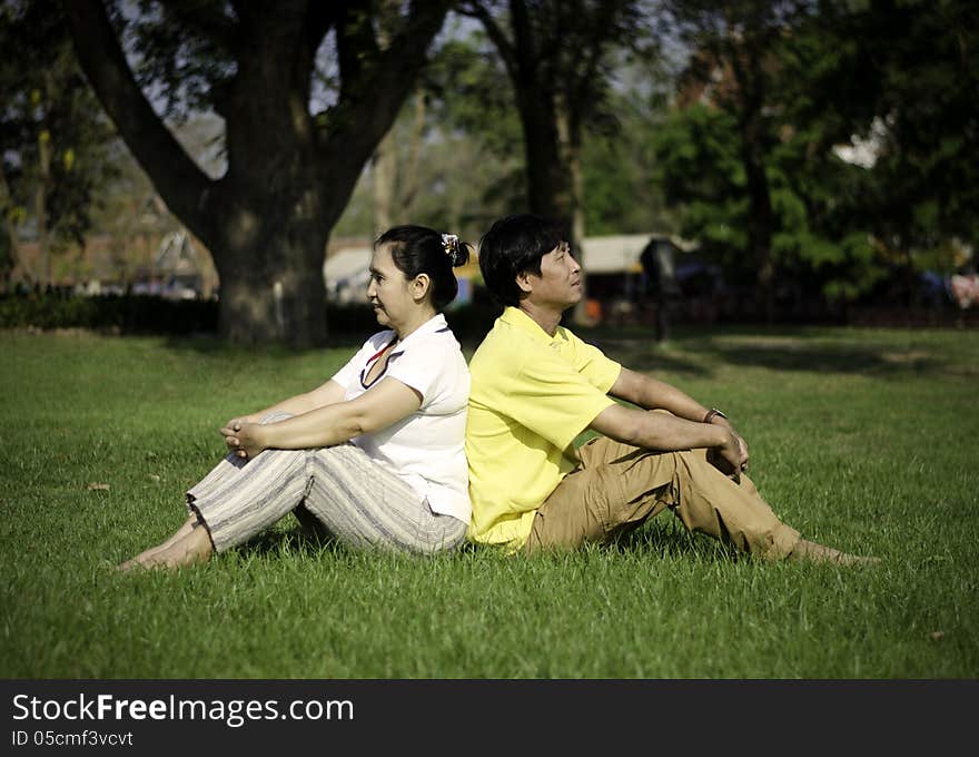 Portrait of beautiful couple sitting on ground in park relaxing