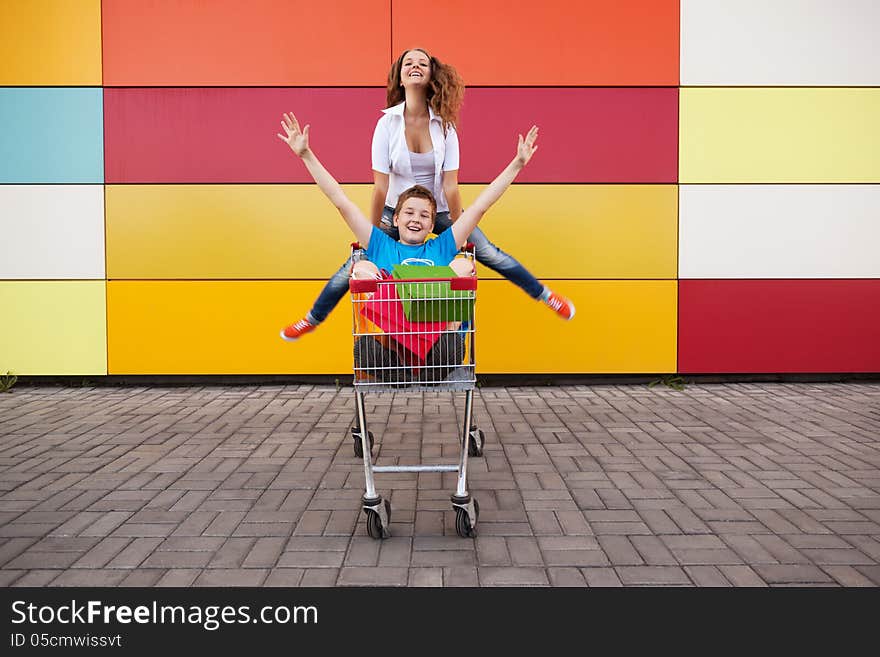 Boy and girl with shopping trolley full of purchases in the street. Boy and girl with shopping trolley full of purchases in the street