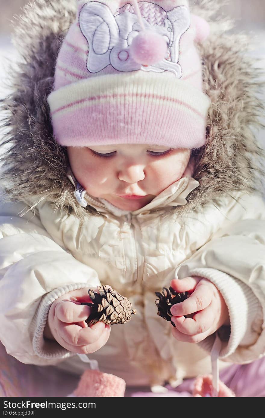 Winter outdoor portrait of little girl playing with cones. Winter outdoor portrait of little girl playing with cones