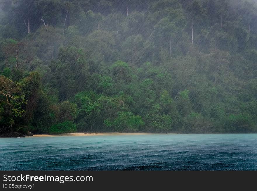 Ocean rain storm detail with green coast background and raindrops