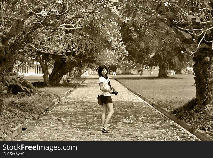 Portrait of sweet young woman standing outdoors and smiling against beautiful nature