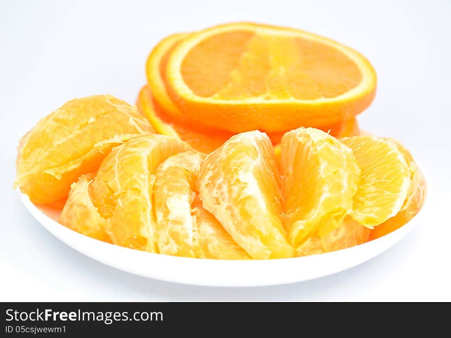 Pieces of orange on the plate and on a white background. Pieces of orange on the plate and on a white background