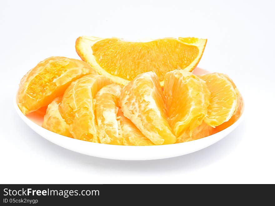 Pieces of orange on the plate and on a white background. Pieces of orange on the plate and on a white background