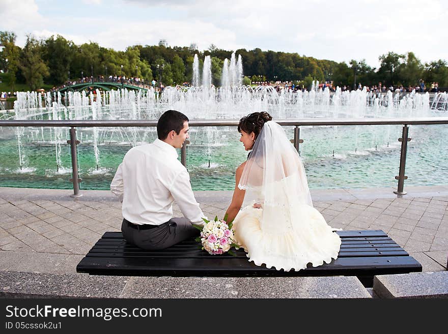 Happy bride and groom near fountain