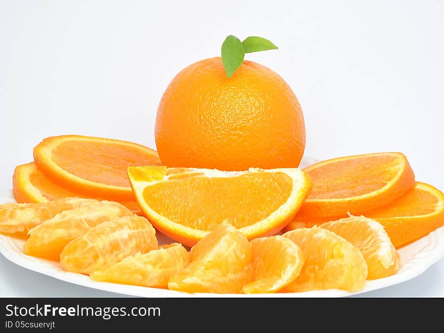 Orange and orange pieces on a plate and white background. Orange and orange pieces on a plate and white background