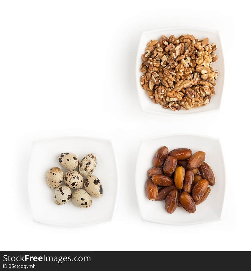 On the white table there are plates of walnuts, quail eggs and dates. You can put your text on free space in the upper left part of the picture. On the white table there are plates of walnuts, quail eggs and dates. You can put your text on free space in the upper left part of the picture.