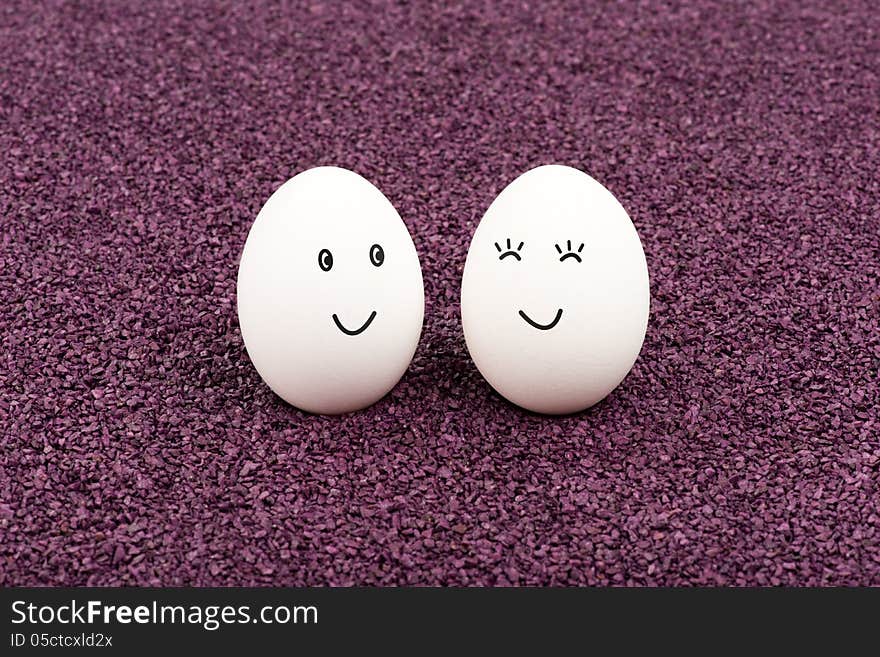 Two white eggs on purple sand smile at each other. Two white eggs on purple sand smile at each other.