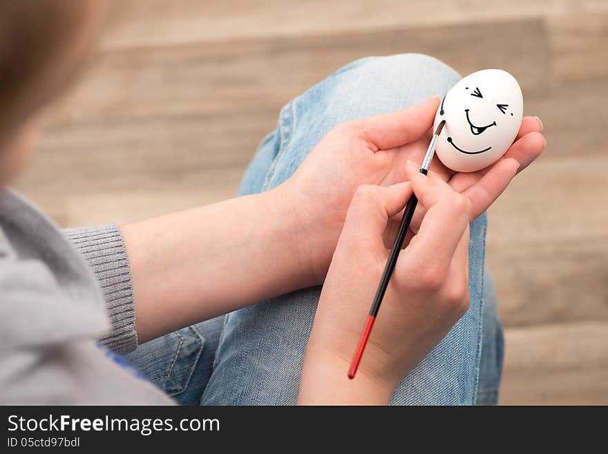 The girl draws with a brush on an white egg. Egg laughs. The girl draws with a brush on an white egg. Egg laughs.