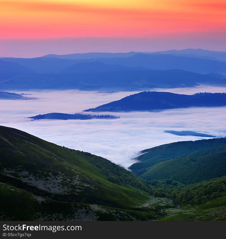 Landscape with bright dawn in the mountains. Morning clouds below the mountains. Landscape with bright dawn in the mountains. Morning clouds below the mountains