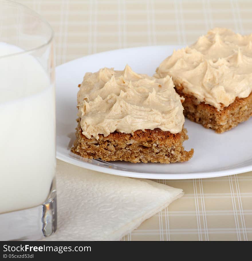 Two peanut butter bars on a plate with a glass of milk. Two peanut butter bars on a plate with a glass of milk