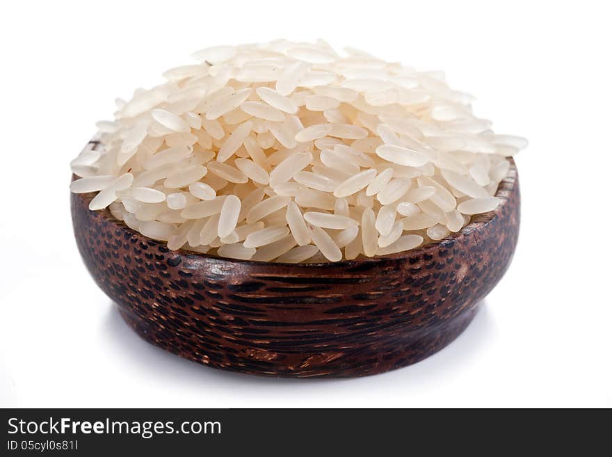 Uncooked rice in a wooden bowl on a white background. Uncooked rice in a wooden bowl on a white background.