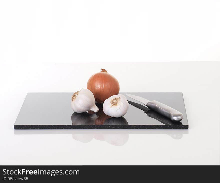 Onions and Garlic on chopping board with knife. Onions and Garlic on chopping board with knife.