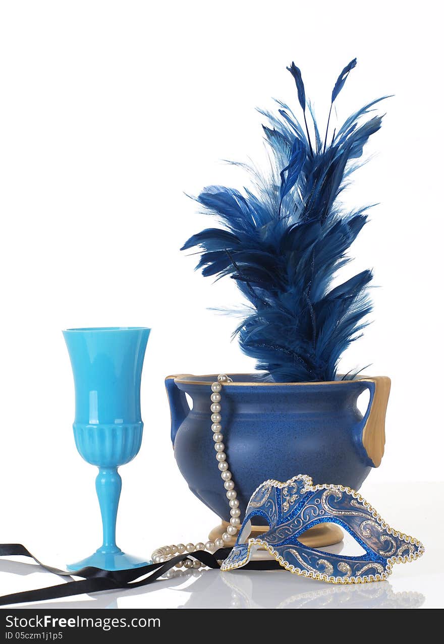 Photo of a blue mask with vase, feather, wine cup, and feathers.