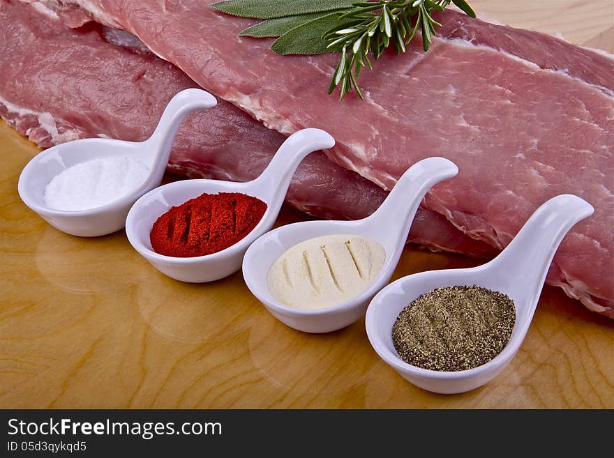 Two pieces of raw pork ribs and spices on a wooden table. Two pieces of raw pork ribs and spices on a wooden table