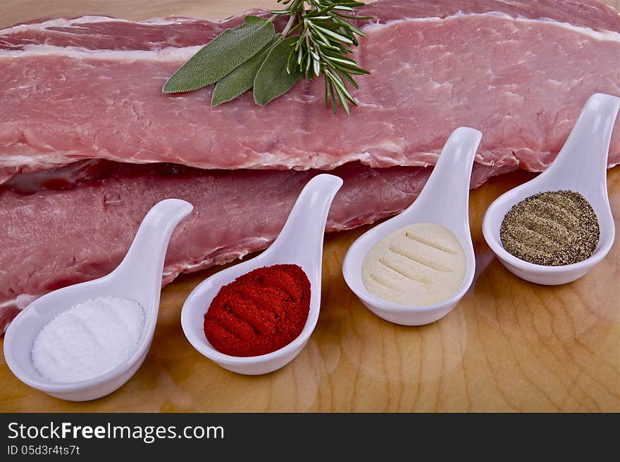 Two pieces of raw pork ribs and spices on a wooden table. Two pieces of raw pork ribs and spices on a wooden table