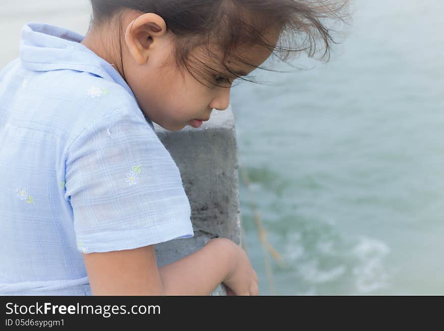 A cute girl is staring to the sea