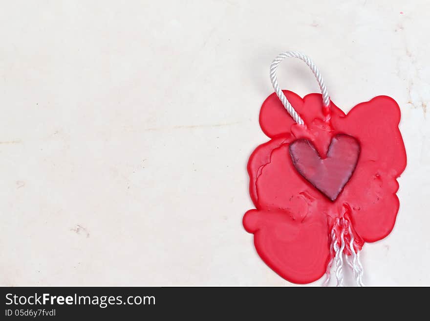 Mark in the shape of a heart made of red wax on the background of old paper. Mark in the shape of a heart made of red wax on the background of old paper