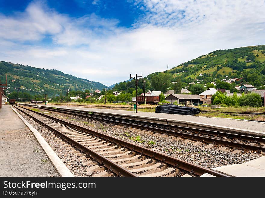 Railroad of railway station in countryside which goes through the mountains under blue sky. Railroad of railway station in countryside which goes through the mountains under blue sky