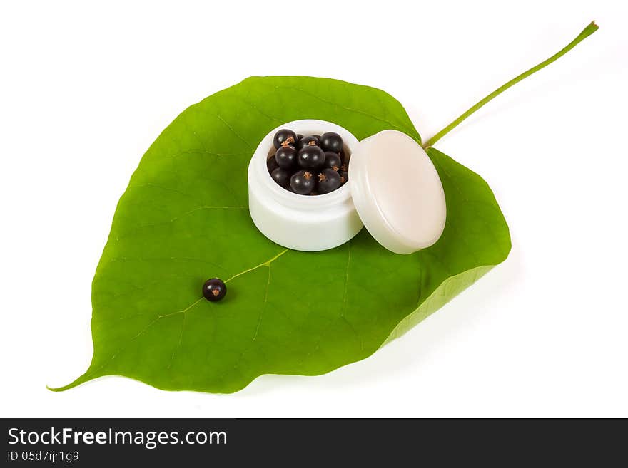 Black currants in a jar of makeup on the big green leaf. Black currants in a jar of makeup on the big green leaf