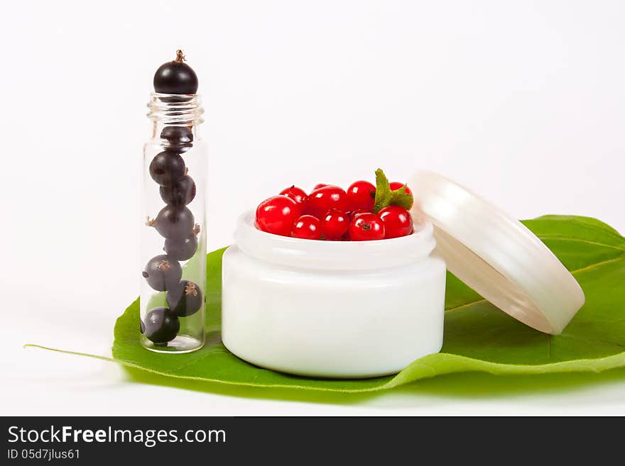 Concept natural cosmetics made of redcurrant and black currant put on white background with green leafs. Concept natural cosmetics made of redcurrant and black currant put on white background with green leafs