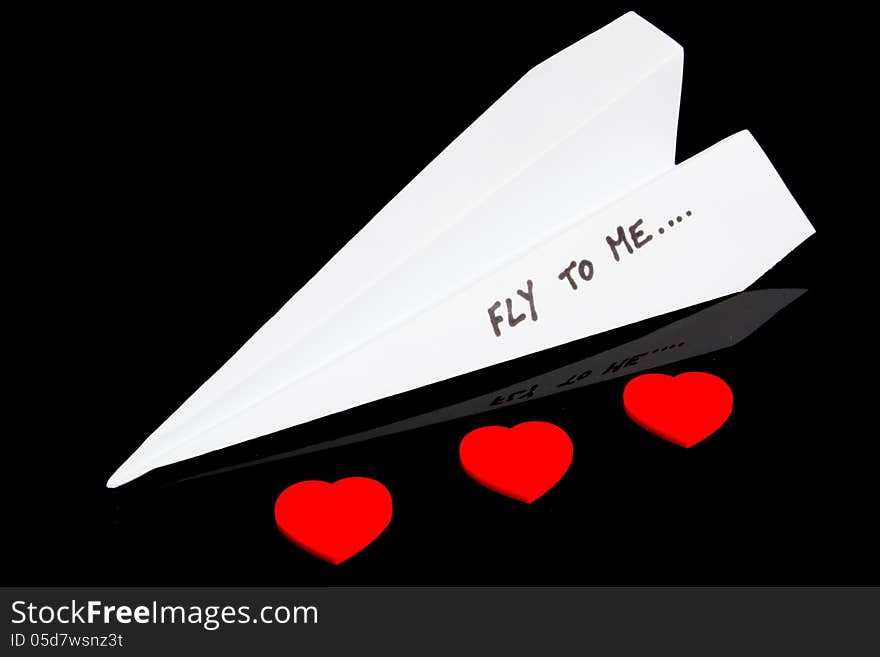 Paper plane and three plastic red hearts