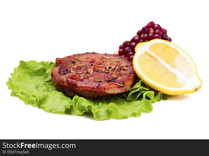 Grilled turkey steak with lemon and pomegranate on leaf of salad. on white background