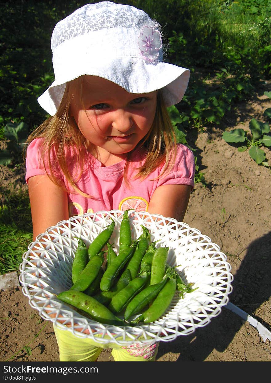 The image of little girl with a plate of peas. The image of little girl with a plate of peas