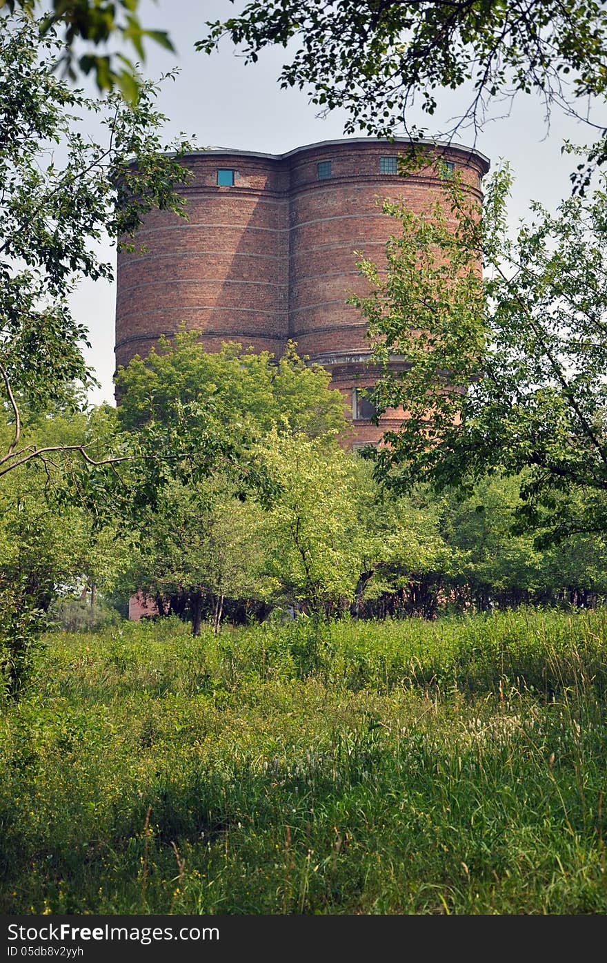 Brick water tower on a background of green trees and grass. Brick water tower on a background of green trees and grass.