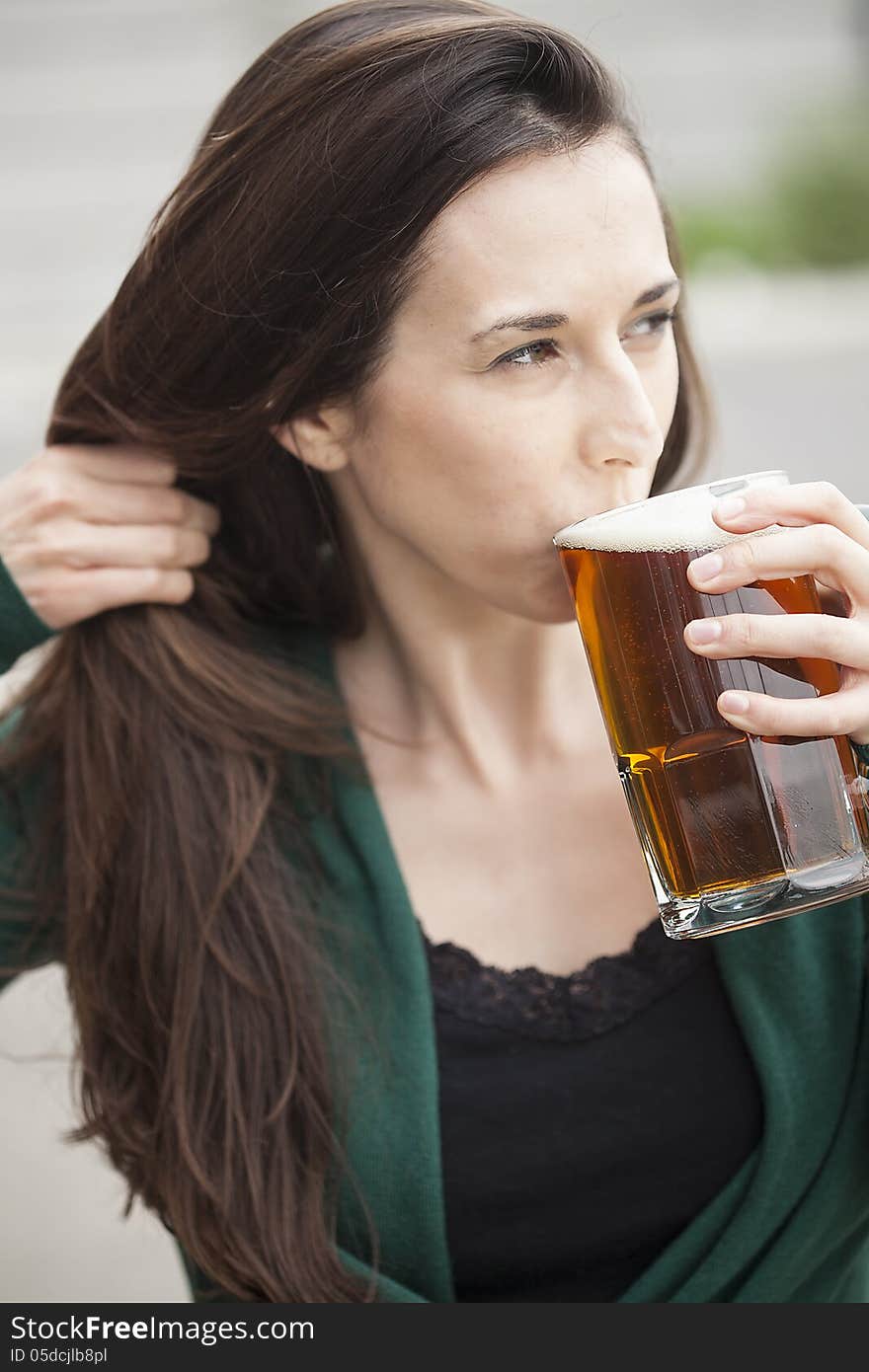 Beautiful young woman with brown hair and eyes holding a mug of beer. Beautiful young woman with brown hair and eyes holding a mug of beer.